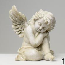 Sivý smútočný anjel s krídlami sediaci na zemi.