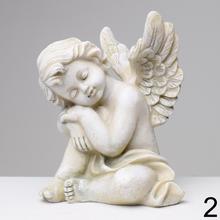 Sivý smútočný anjel s krídlami sediaci na zemi.