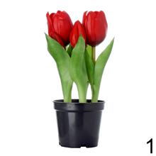 Umelé tulipány v čiernom kvetináči.