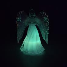 Sviečka v tvare anjela s bielymi krídlami.