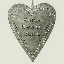 Plechové srdce s nápisem 'Home Sweet Home'.