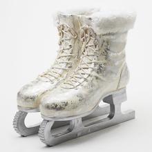 Bílé brusle s kožešinou na stříbrném podstavci.