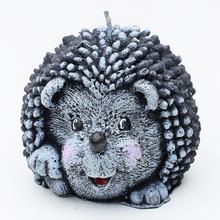 Šedá figurka ježka, svíčka.