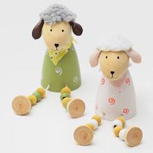 Dřevěná ovečka sedící s barevnými kuličkami.