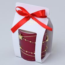 Vonná svíčka v bordovém skle s červenou stuhou.