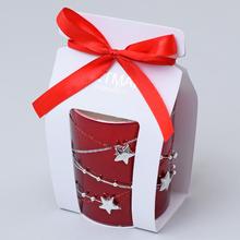 Červená vonná svíčka ve skle s ozdobnou stužkou.