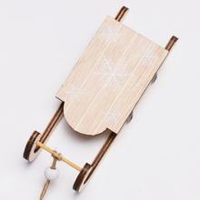 Dřevěné saně v přírodní barvě s bílými vzory.