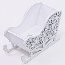 Bílé dřevěné saně s vyřezávanými sněhovými vločkami.