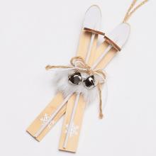 Závěsné lyže s dekorativními zvonečky a bílou sněhovou vločkou.