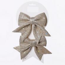 Sada dvou zlatých mašlí s třpytkami.