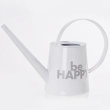 Bílá konvička s nápisem 'be HAPPY'.