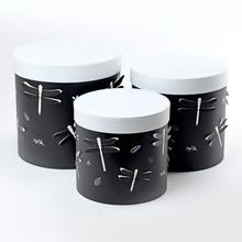 Dárková krabička se třemi černými válci s bílým vrchem.