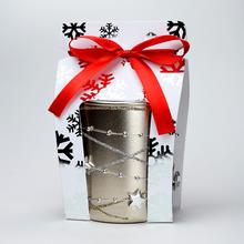 Vánoční svíčka ve skleněném obalu s dekorací a červenou stuhou.