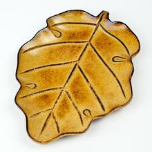 Hnědý tác ve tvaru listu vyrobený z MDF dřeva.