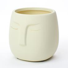 Bílý květináč s otvorem a tváří.