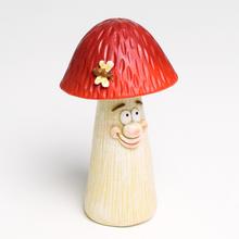 Dekorace muchomůrka s červenou čepicí a usměvavou tváří.