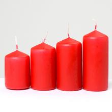 Sada červených adventních svíček různých velikostí.