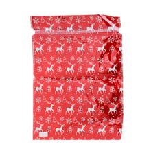 Červený vánoční sáček s motivem jelena a sněhových vloček.