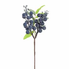 Umělá větvička se zelenými listy a modrými bobulemi.