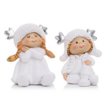 Dvě děti sedící s čepicemi a parohy, bílé keramické dekorace.