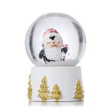 Sněhová koule s tučňákem v bílé, zlaté a červené barvě.