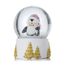 Sněhová koule s tučňákem v červené čepici.