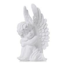 Bílý smuteční anděl sedící s křídly.