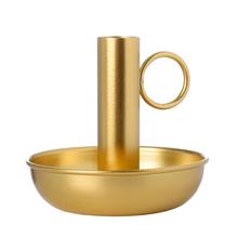 Zlatý kovový svícen s držadlem.