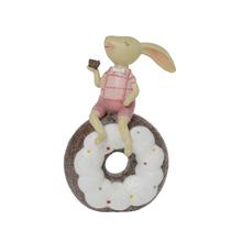 Růžový zajíček sedící na donutu.