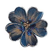 Umělá květina na klipu v zelené barvě s ozdobnými detaily.