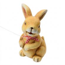 Keramický zajíček s červenou mašlí.